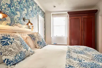 a bedroom with a bed with blue and white pillows at Ocean Villas in Marazion