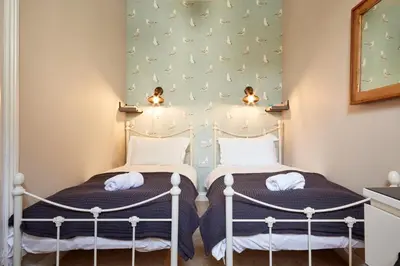 two beds in a room with a wall with butterflies at Ocean Villas in Marazion