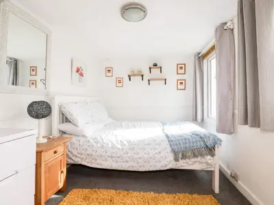 a white bedroom with a bed and a mirror at The Moonbeach Cabin in Gorran Haven