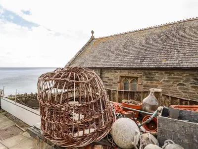 a bird cage sitting on the ledge of a house at The Moonbeach Cabin in Gorran Haven