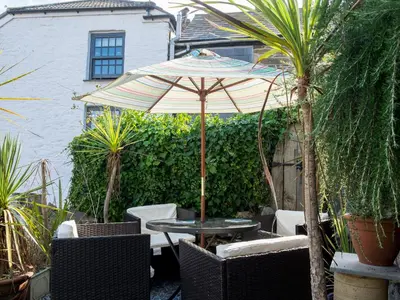 a patio with a table and chairs and an umbrella at The Moonbeach Cabin in Gorran Haven