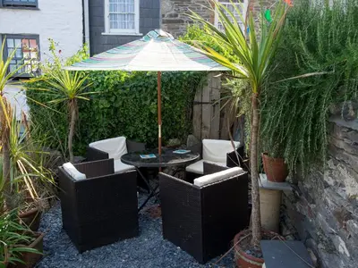a patio with a table and chairs and an umbrella at The Moonbeach Cabin in Gorran Haven