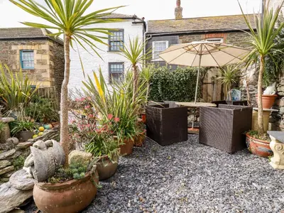 a garden with palm trees and a table with an umbrella at The Moonbeach Cabin in Gorran Haven