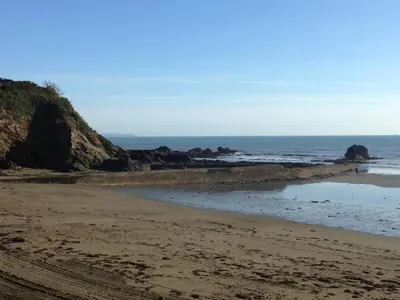 a sandy beach with rocks in the ocean at Bay View, Millendreth Looe Cornwall in Looe