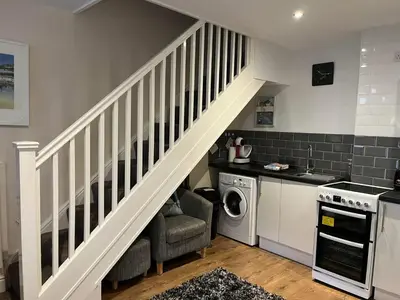 a staircase in a kitchen with a washing machine at Seagull Cottage in Looe