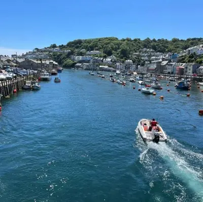 a boat traveling down a river with a bunch of boats at Seagull Cottage in Looe