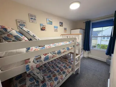 a bedroom with two bunk beds and a window at Seagull Cottage in Looe