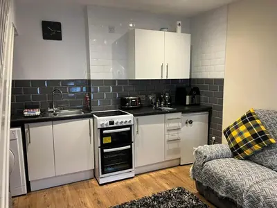 a small kitchen with white appliances and a couch at Seagull Cottage in Looe