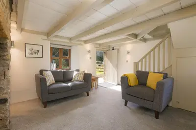 a living room with two chairs and a staircase at The Annex - Trewolla Cottage in Newquay