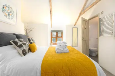 a bedroom with a large bed with a yellow blanket at The Annex - Trewolla Cottage in Newquay