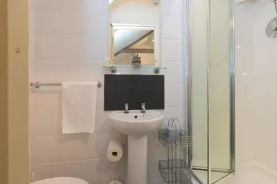 a white bathroom with a sink and a shower at The Annex - Trewolla Cottage in Newquay
