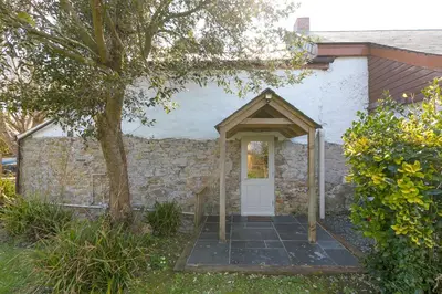 a house with a white door and a stone wall at The Annex - Trewolla Cottage in Newquay