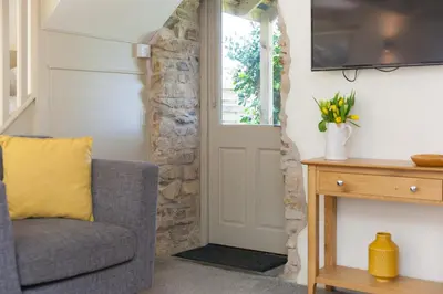 a living room with a chair and a door at The Annex - Trewolla Cottage in Newquay