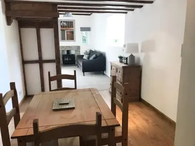 a living room with a table and chairs and a couch at Woodland cottage in Cornwall with walled garden in Helston