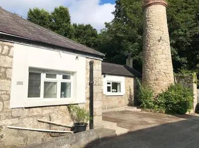 a brick house with a chimney and a window at Woodland cottage in Cornwall with walled garden in Helston