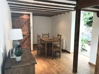 a dining room with a table and chairs and a barn door at Woodland cottage in Cornwall with walled garden in Helston