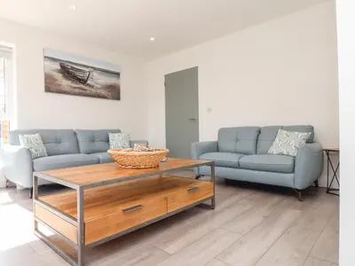 a living room with two blue couches and a table at Amal Anpras in Tintagel