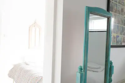 a mirror sitting next to a bed in a room at Pollymoor Beach House in Holywell Bay