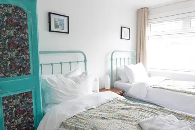 a bedroom with two beds and a window at Pollymoor Beach House in Holywell Bay