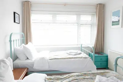 two beds in a bedroom with a window at Pollymoor Beach House in Holywell Bay