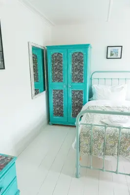 a bedroom with a bed and a blue door at Pollymoor Beach House in Holywell Bay