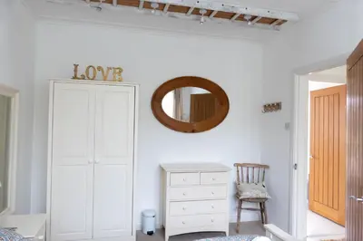 a bedroom with a white cabinet and a mirror at Hoblyns Cove in Holywell Bay