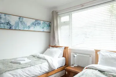 two twin beds in a room with a window at Hoblyns Cove in Holywell Bay