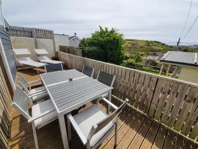 a wooden deck with a table and chairs on it at Hoblyns Cove in Holywell Bay