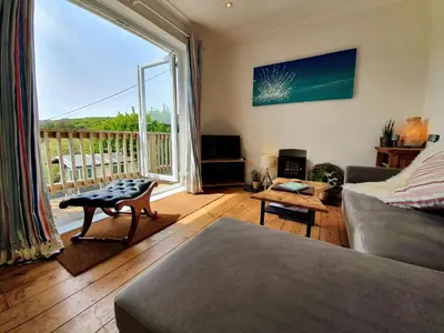 a living room with a couch and a large window at Hoblyns Cove in Holywell Bay