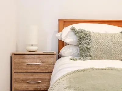 a bedroom with a bed with a dresser and a lamp at Lighthouse Lofts - Godrevy in Camborne