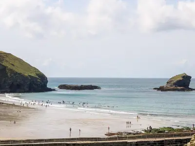 a group of people on a beach near the ocean at Lighthouse Lofts - Godrevy in Camborne