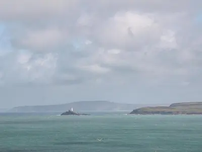 a lighthouse on an island in the middle of the ocean at Lighthouse Lofts - Godrevy in Camborne