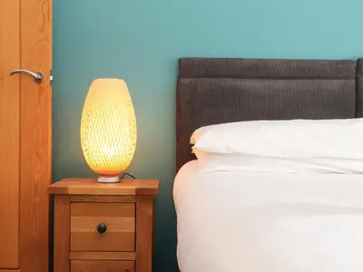 a lamp on a night stand next to a bed at 11 Towan Valley in Truro