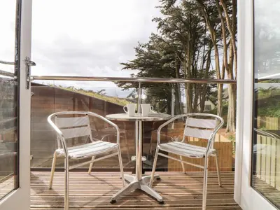 a patio with two chairs and a table on a deck at 11 Towan Valley in Truro