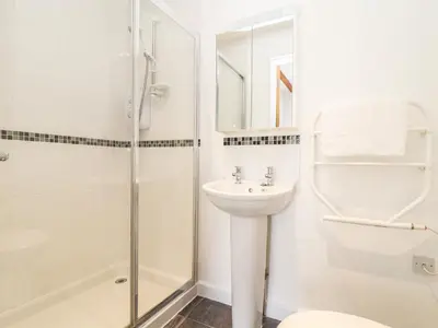 a white bathroom with a shower and a sink at 11 Towan Valley in Truro