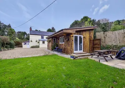 a small house with a picnic table in a yard at Minimoor Lodge in Scorrier
