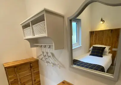 a mirror on a wall with a bed in a room at Minimoor Lodge in Scorrier