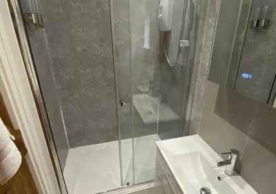 a shower with a glass door next to a sink at Minimoor Lodge in Scorrier