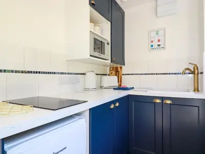 a kitchen with blue cabinets and white appliances at Peony Cottage in St Austell