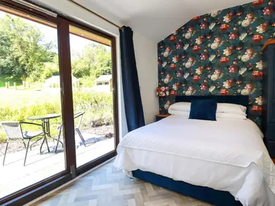 a bedroom with a bed and a large window at Peony Cottage in St Austell