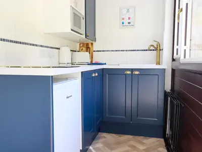 a kitchen with blue cabinets and a sink at Peony Cottage in St Austell