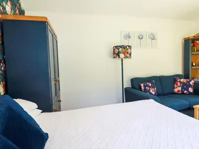 a bedroom with a bed and a blue couch at Peony Cottage in St Austell