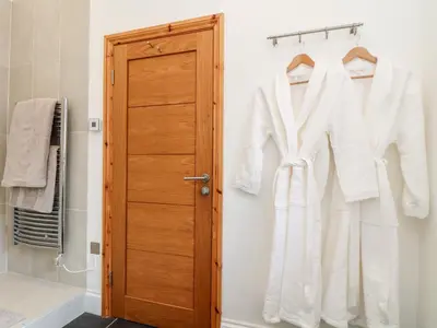 a bathroom with white clothes hanging on a door at Rosewarrick Cottage in Bodmin