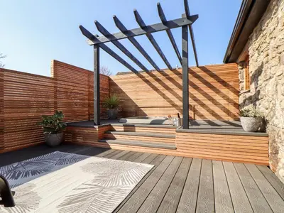 a wooden deck with a pergola and a hot tub at Rosewarrick Cottage in Bodmin