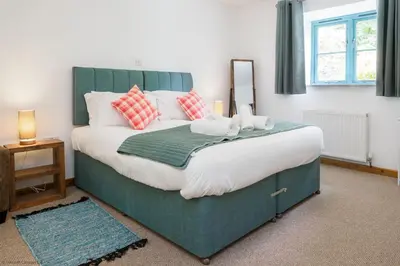 a bedroom with a large bed with pillows and a mirror at Budock Cottage in Mawnan