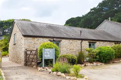 a stone building with a sign in front of it at Budock Cottage in Mawnan