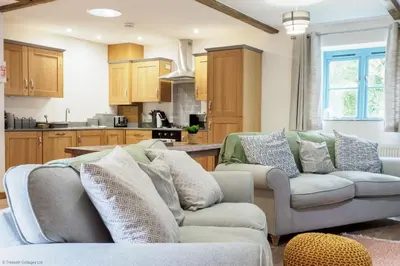 a living room with two couches and a kitchen at Budock Cottage in Mawnan