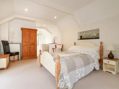 a bedroom with a bed and a desk and a chair at Blue Bell Cottage in St Austell