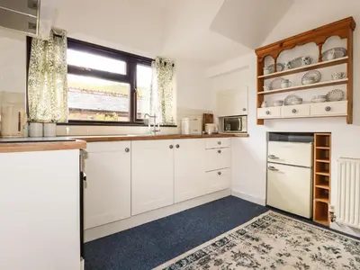a kitchen with white cabinets and a window at Blue Bell Cottage in St Austell