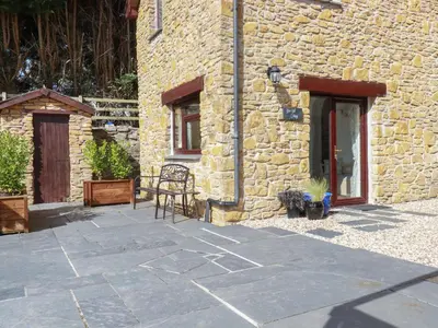 a stone patio in front of a stone building at Blue Bell Cottage in St Austell